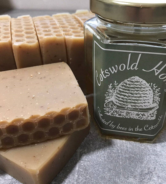 Jar of Cotswold Honey with honeycomb-patterned soap bars on a gray surface