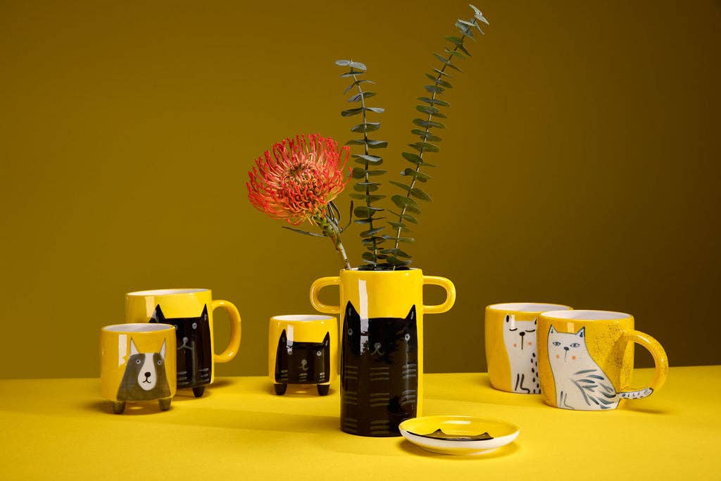Yellow vase with handles and black cat illustration.