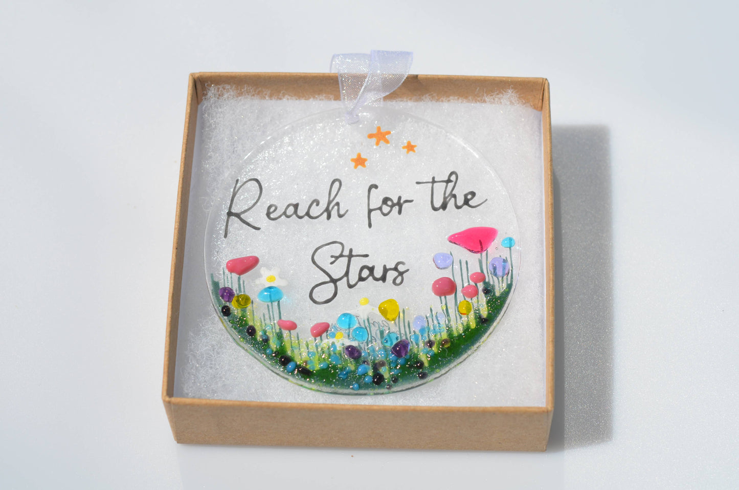 Decorative hanging with 'Reach for the Stars' text and colorful flowers in a box on a white background