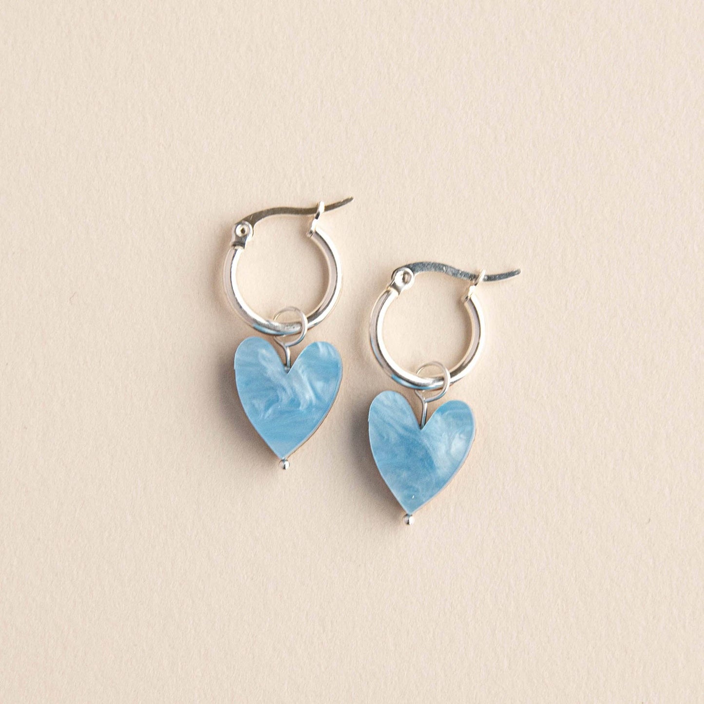 Heart-shaped earrings with blue stones on a beige background