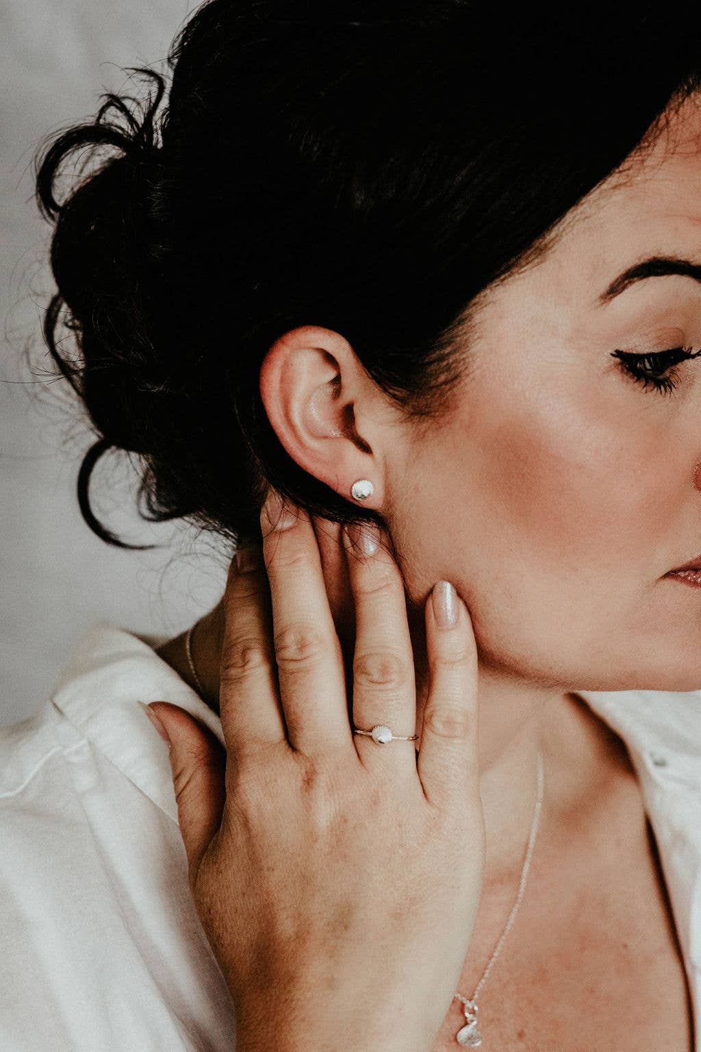 Close-up of a woman adjusting an earring with a blurred background