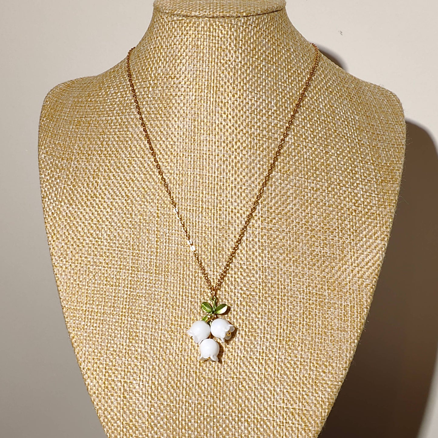 Glass lily of the valley charm hanging on gold plated chain.