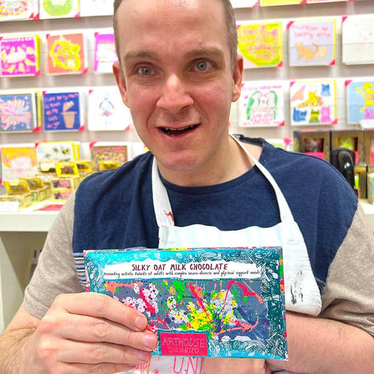 Person holding a product package in a store setting with colorful products in the background
