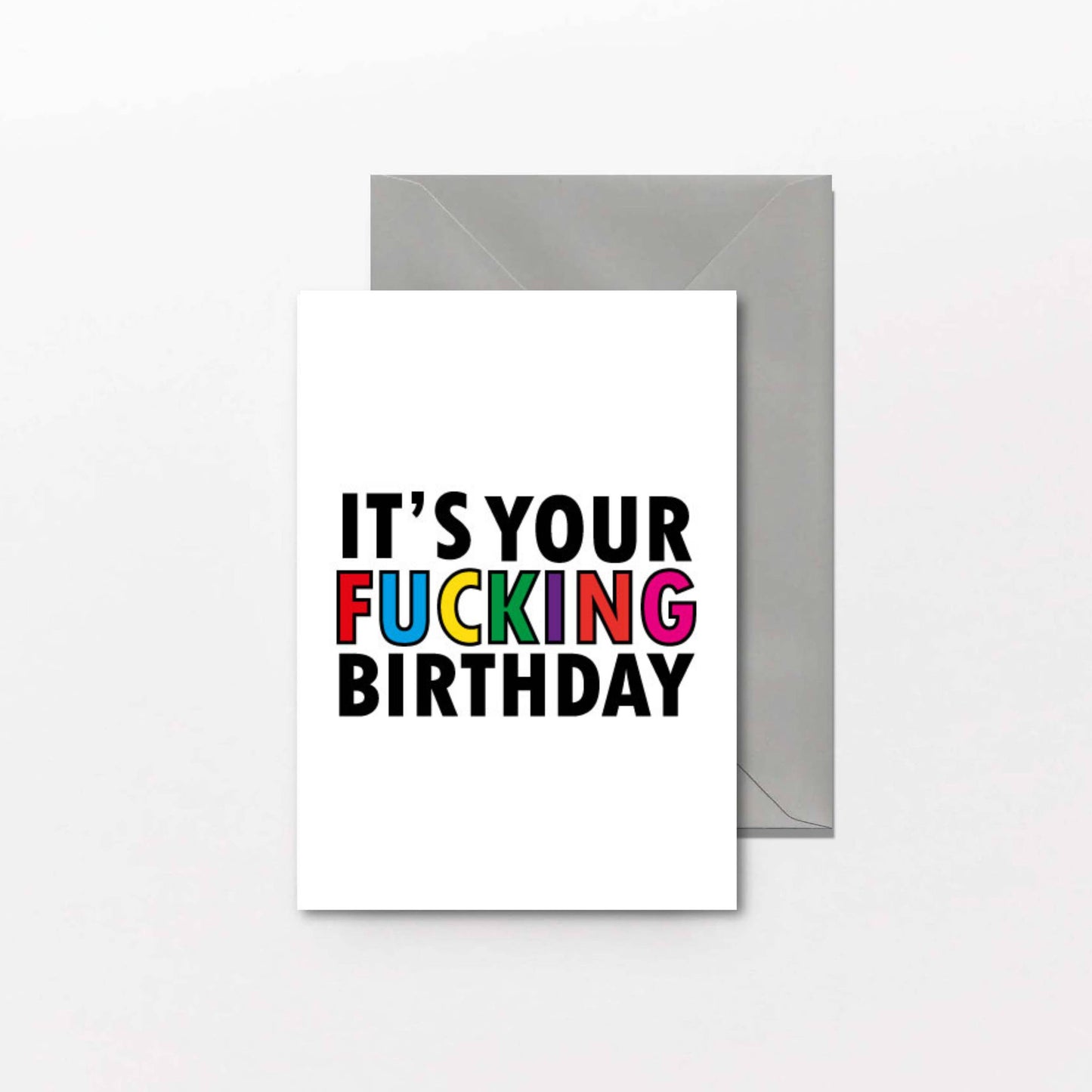 Greeting card with colorful text 'IT'S YOUR FUCKING BIRTHDAY' on a white background with a gray envelope.