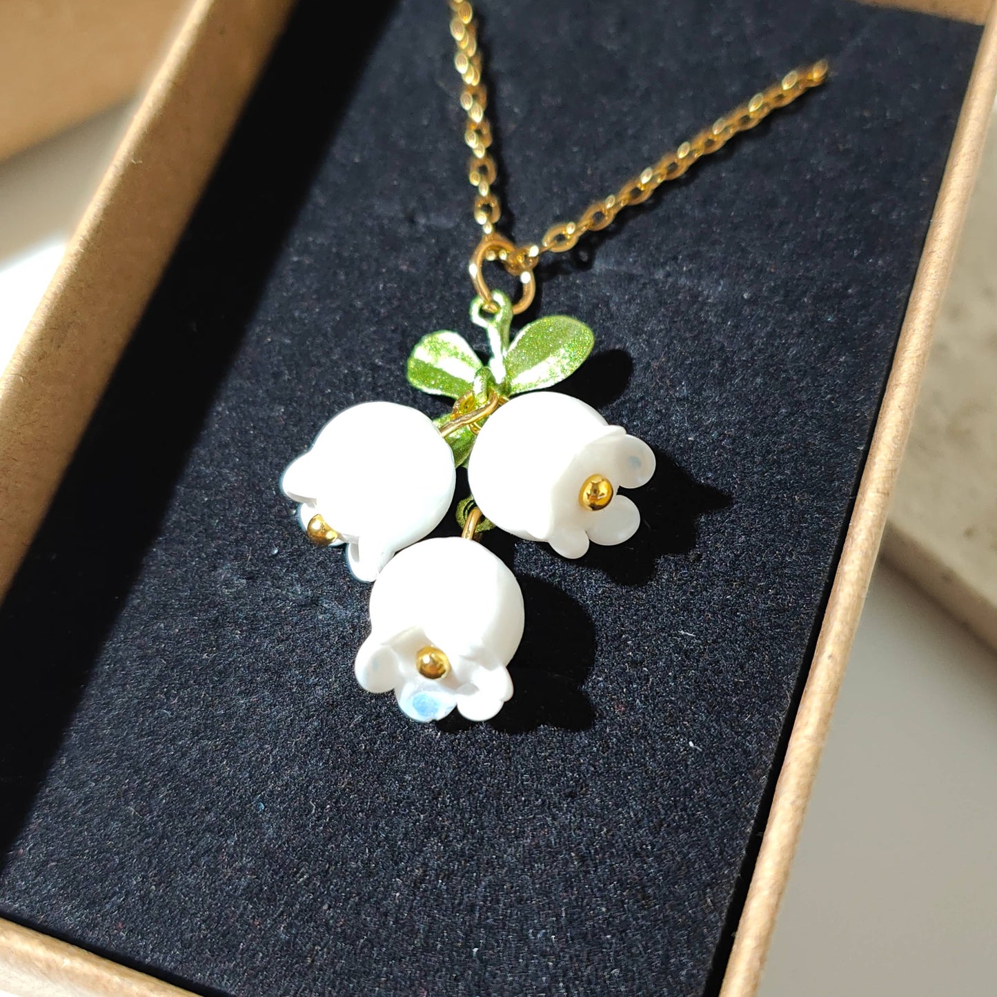 Glass lily of the valley charm hanging on gold plated chain.