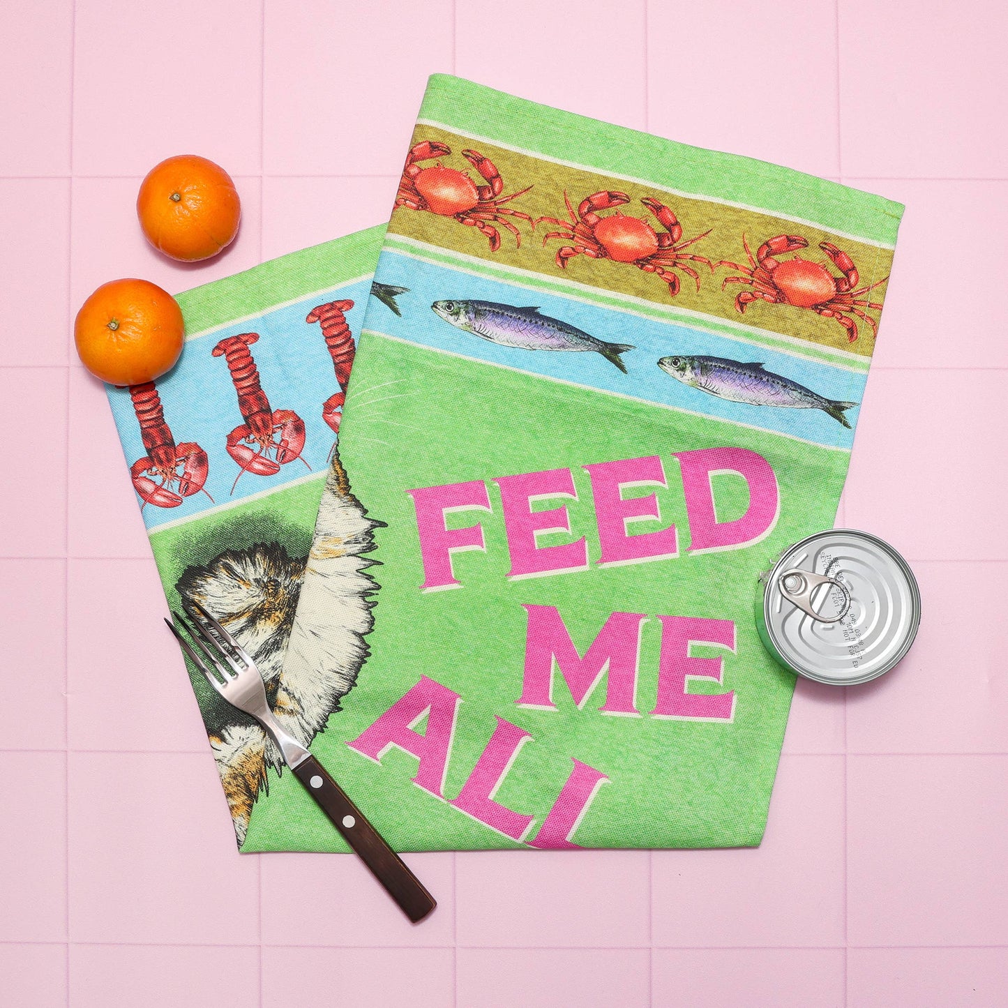 Two colorful placemats with animal illustrations and text on a pink tiled surface.