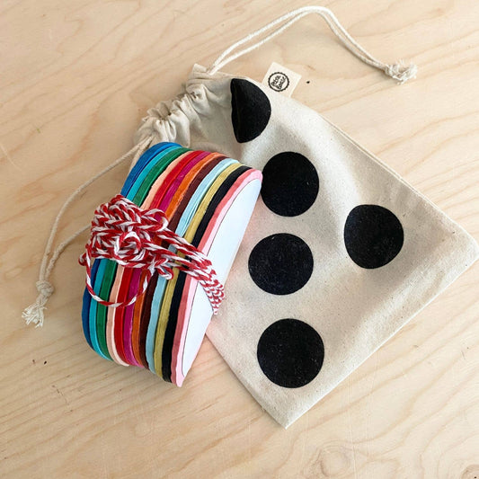 Colorful striped bracelet and black polka dot pouch on a wooden surface
