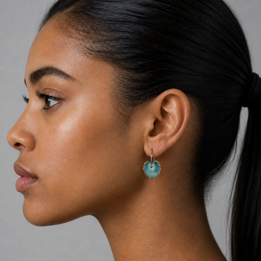 Close-up of a woman wearing a blue heart-shaped earring against a gray background