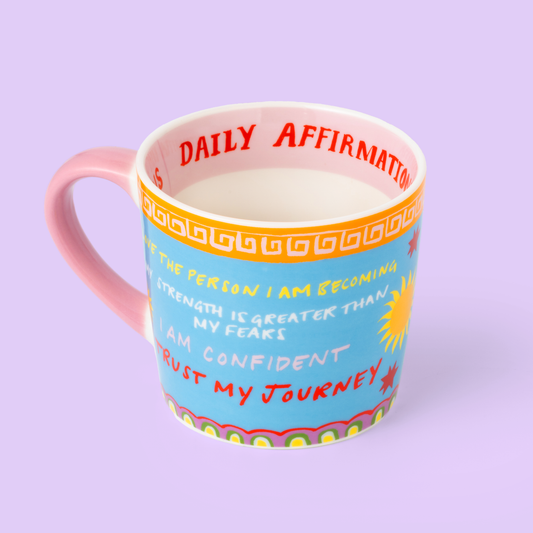 Colorful mug with text and a pink handle on a light purple background