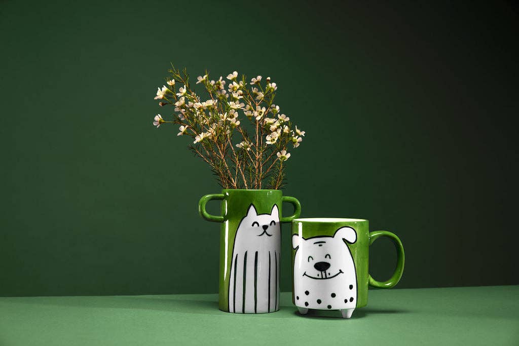 Green vase with cat design and green mug with dog design on a green background