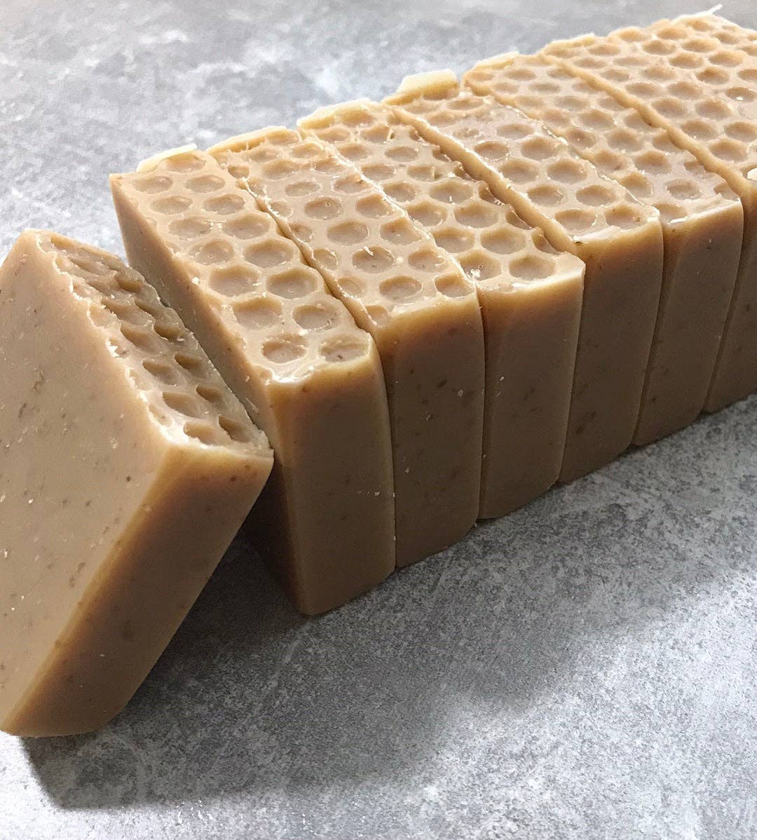 Beige honeycomb-patterned soap bars on a gray surface