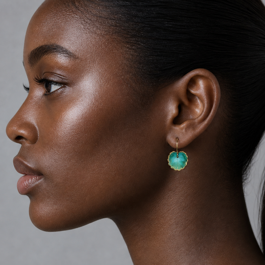 Close-up of a woman wearing a green earring against a neutral background