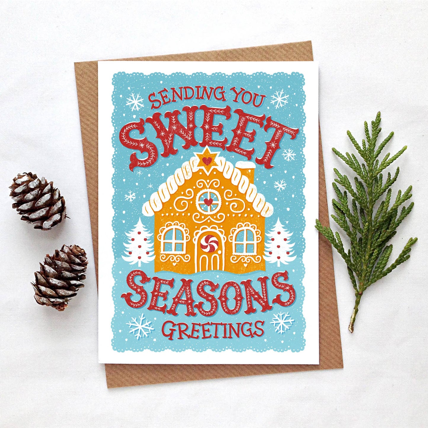 Christmas Cards. Blank inside. Gingerbread house on a turquoise background with snowflakes. Text is Sending you sweet seasons greetings.