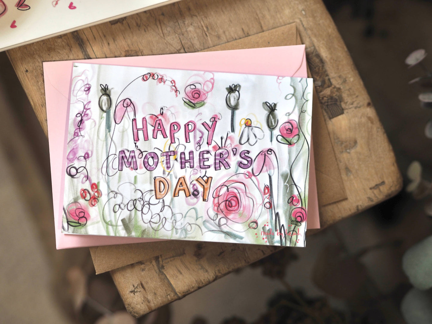 Handmade Mother's Day card with floral designs on a wooden surface