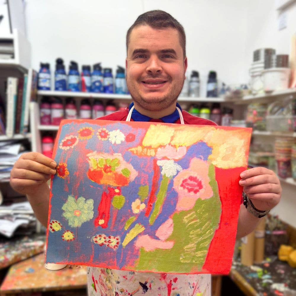 Person holding a colorful painting in a store setting