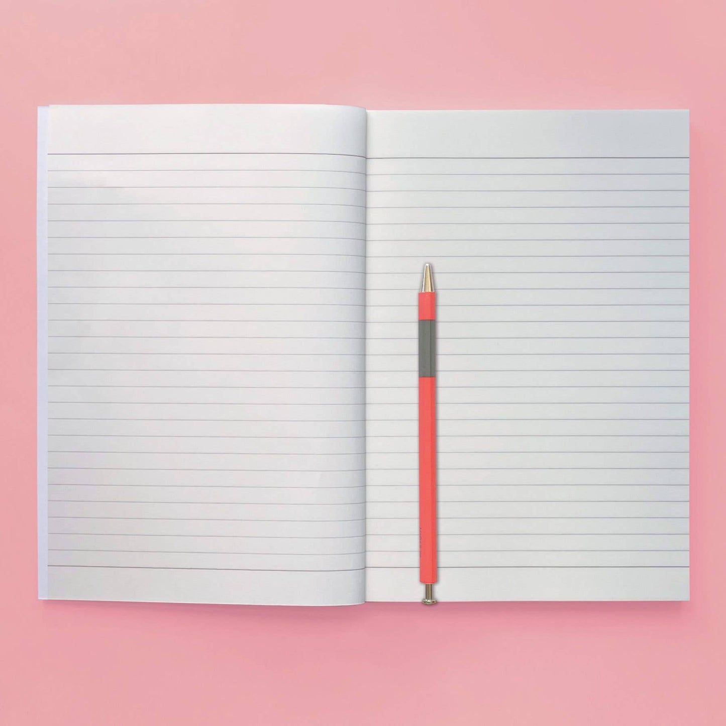 Open notebook with a red pen on a pink background
