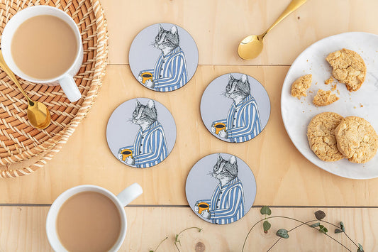 Four round coasters featuring an illustration of a cat in blue striped pyjamas holding a mug of coffee.