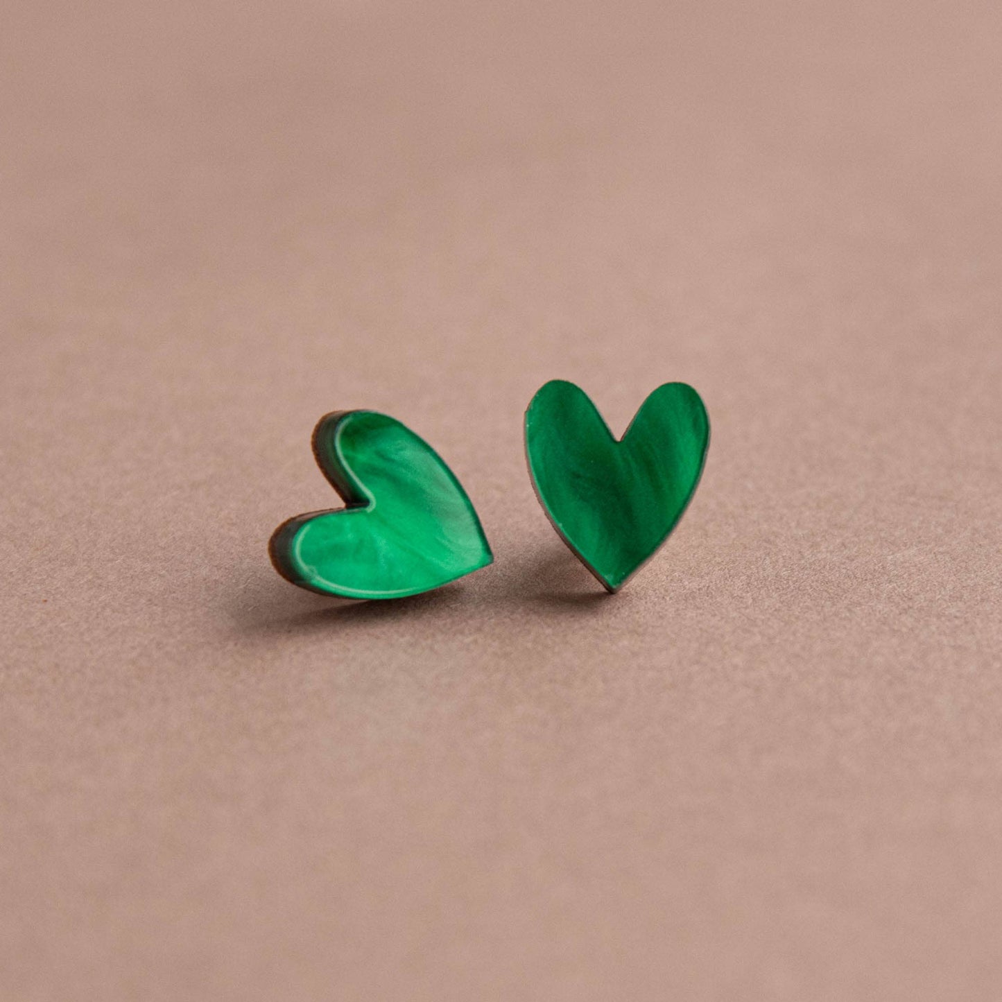 Green heart-shaped earrings on a beige background
