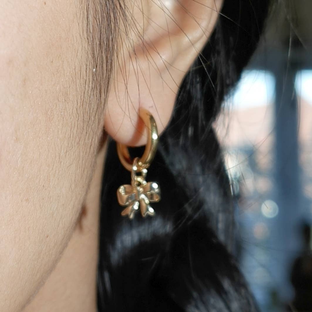 Gold plated hoop earrings with a bowtie ribbon charm