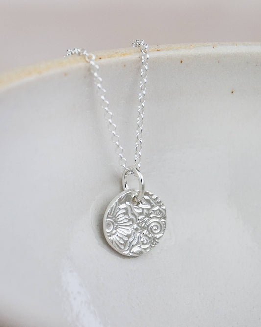 Silver necklace with a detailed pendant on a light background