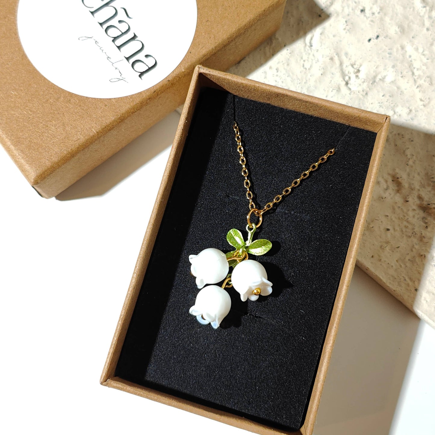 Glass lily of the valley charm hanging on gold plated chain.