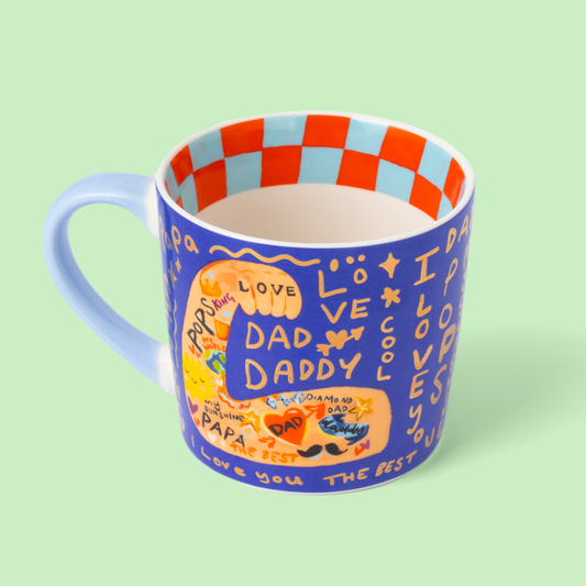 Blue mug with colorful text and graphics on a light green background
