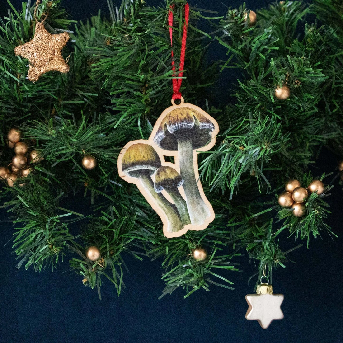 A wooden Christmas decoration of a Parasol mushroom, threaded with a bright red ribbon.