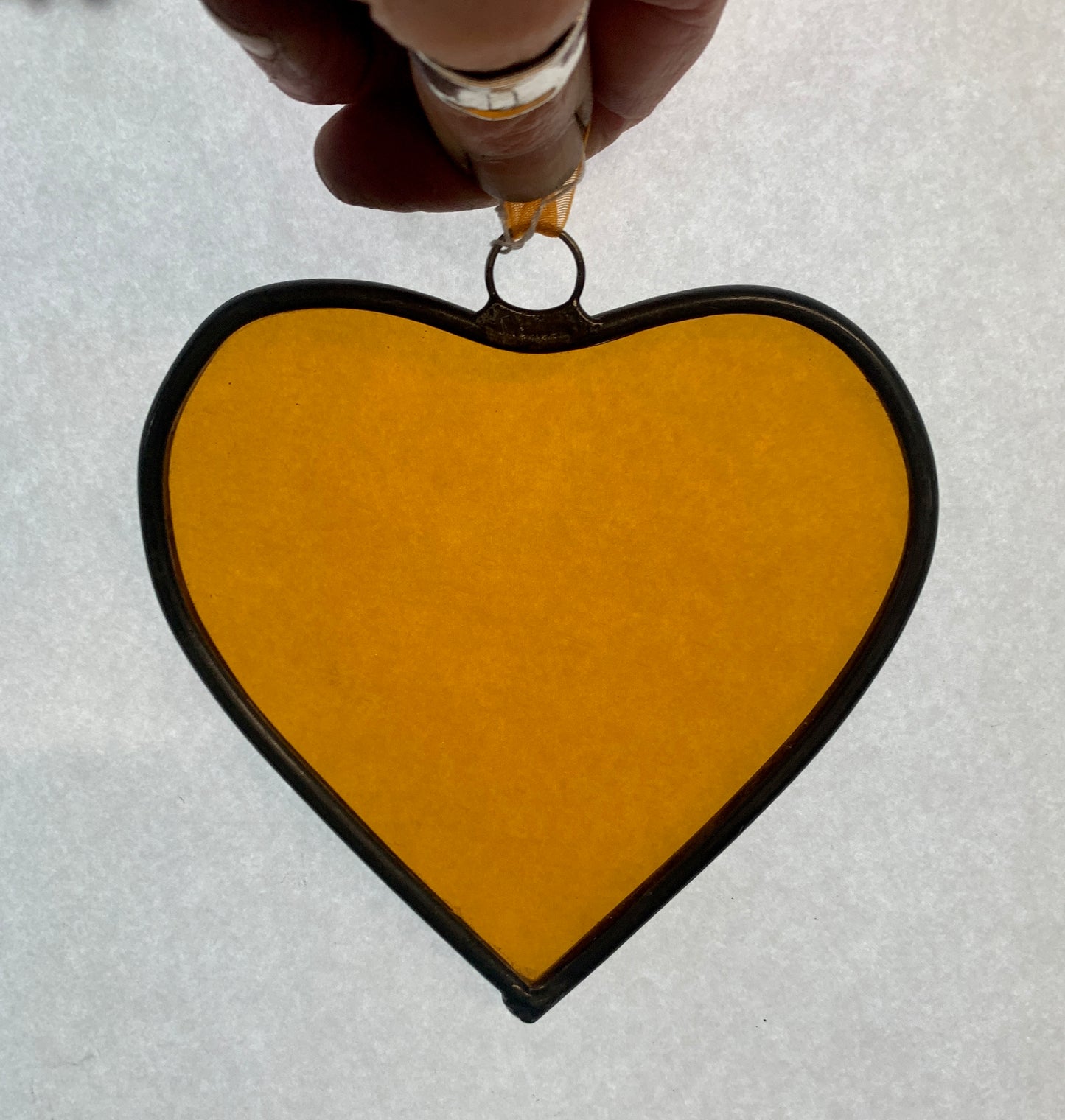 A medium sized Glass heart with a lead edging and a copper wire hook to hang in a window or outside in a tree