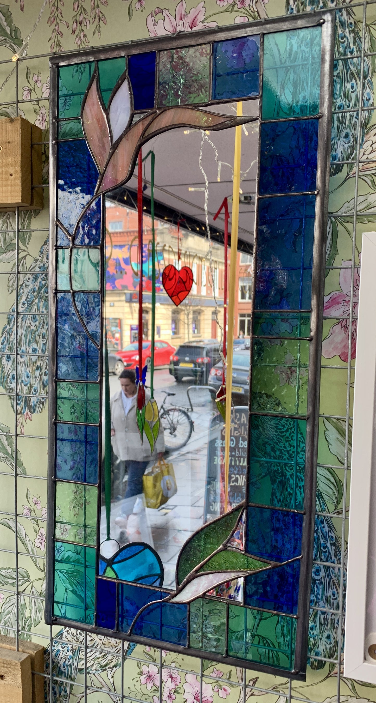 Stained Glass Mirror. Blue and Turquoise border glass; Irridiscent glass floral petals. Made by Dadswell Glass.