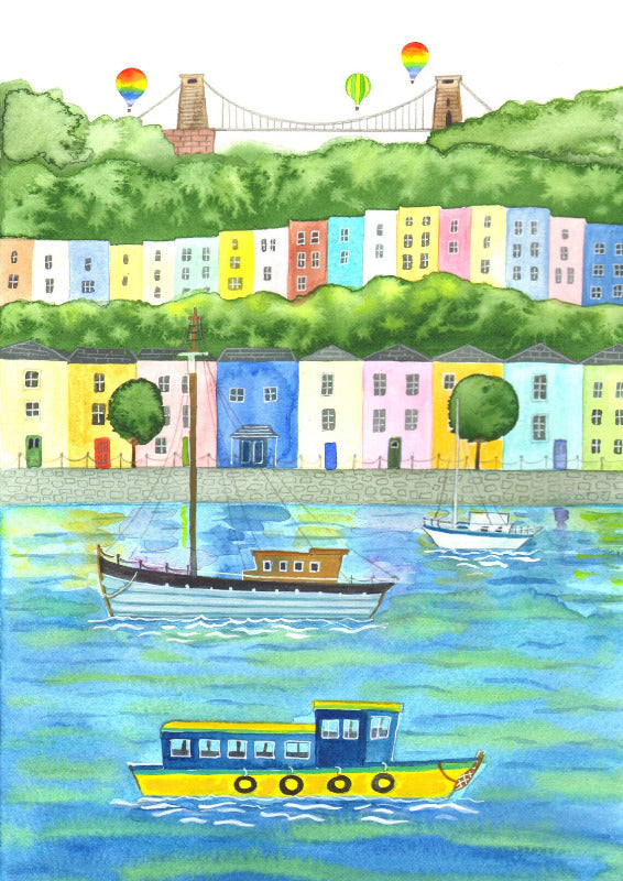 A view of Bristol harbour with boats in foreground and coloured houses, Clifton Suspension Bridge and balloons in the background