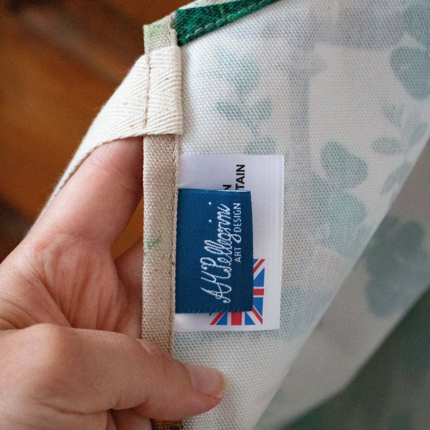 A close-up view of a blue label on the inside of an apron with the logo "AM Pellegrini Art & Design"