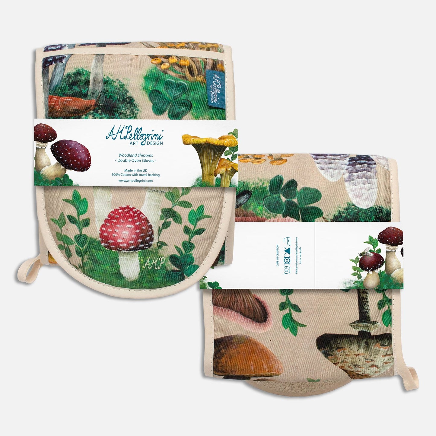 An image showing the front and back of a pair of folded oven gloves wrapped with a paper band. The oven gloves have a design depicting hand-painted woodland mushrooms against a sandy beige background. The paper band depicts the artist's logo and product information (front) and care instructions (back).