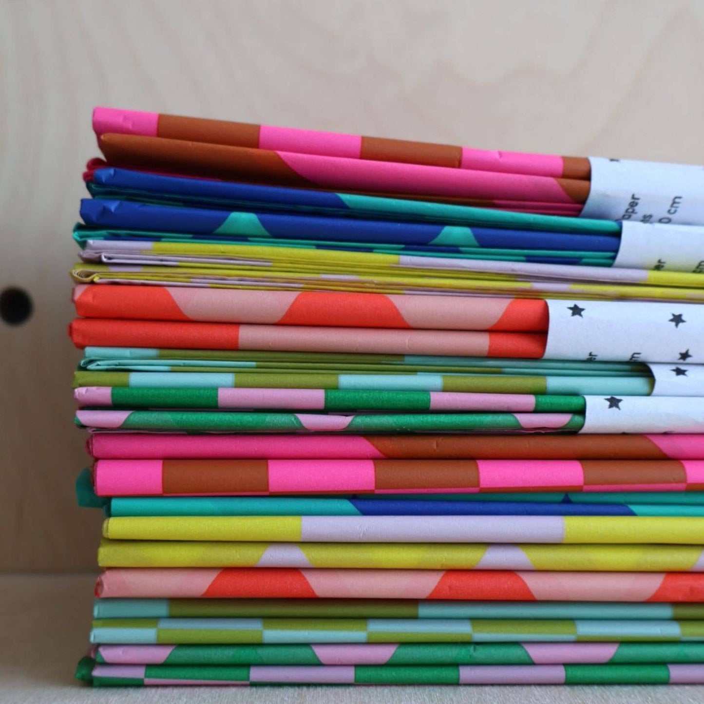 Stack of colorful notebooks with various patterns on a neutral background