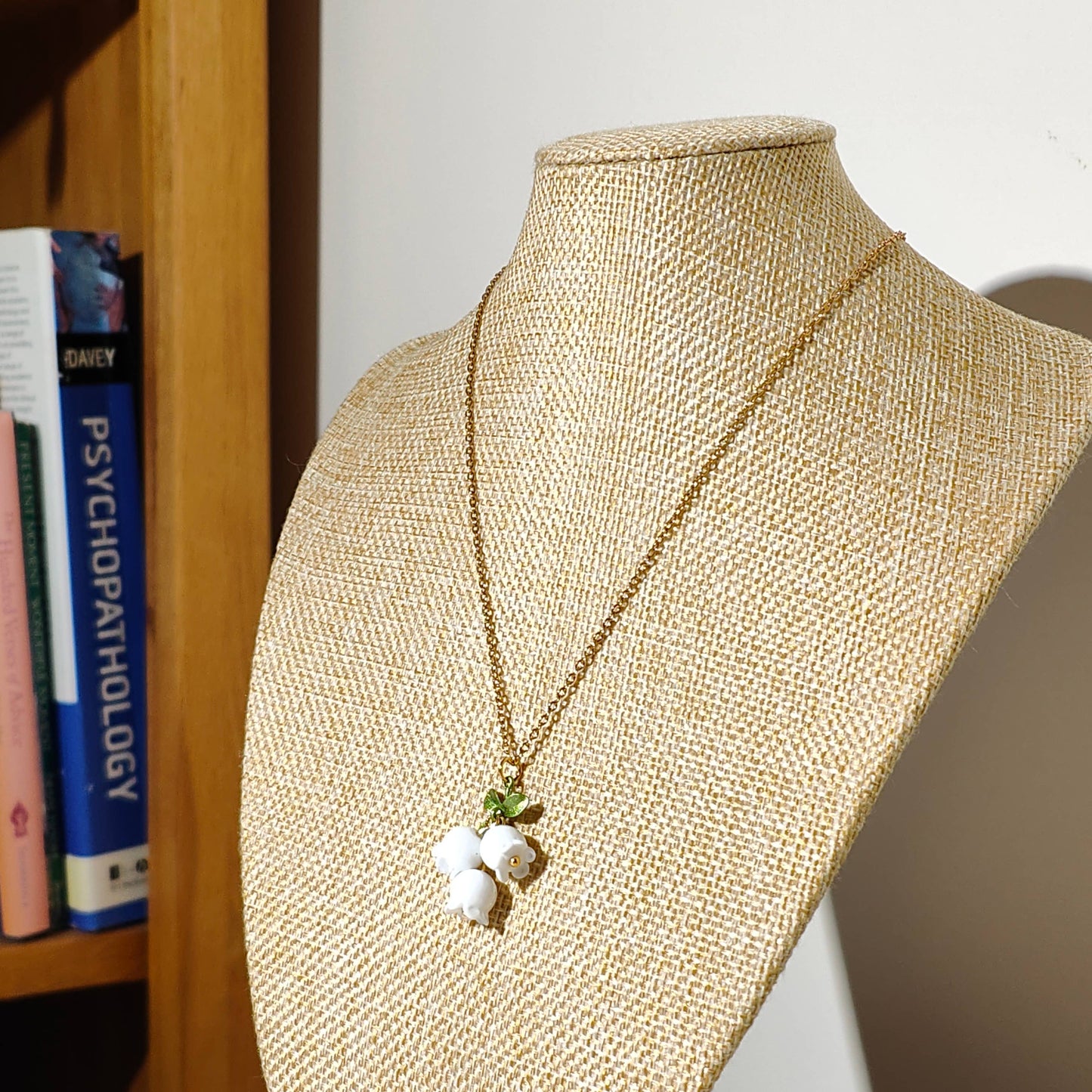 Glass lily of the valley charm hanging on gold plated chain.