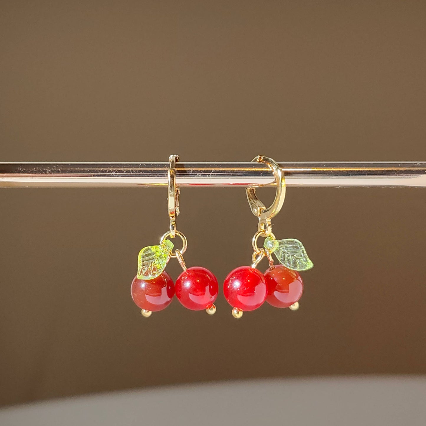 Semi precious stone cherry charms hanging on gold plated hoops.