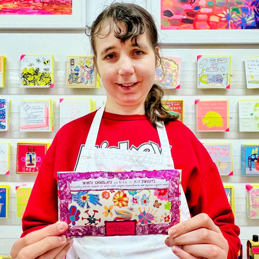 Person holding a colorful product package in front of a wall of similar products