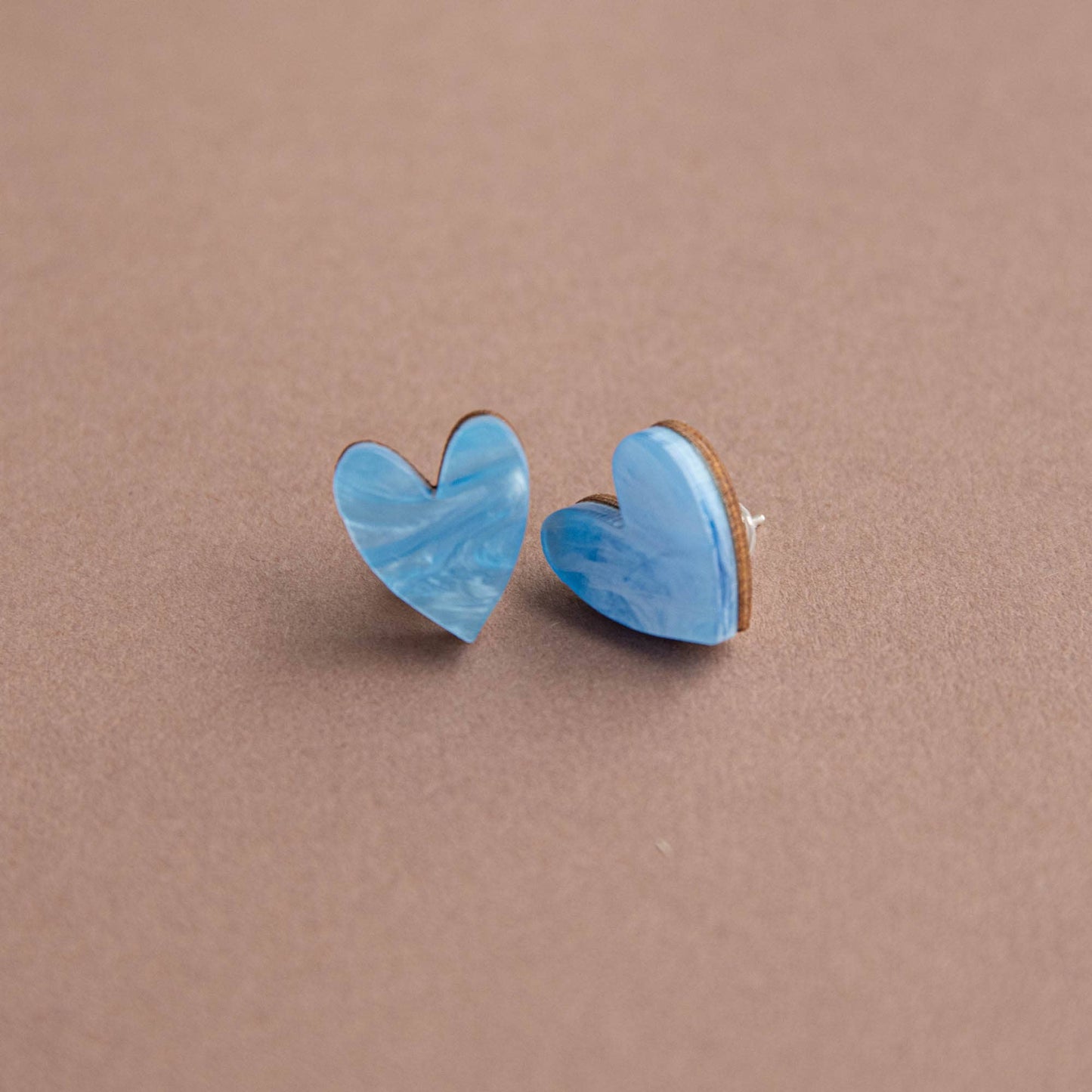 Blue heart-shaped earrings on a brown background