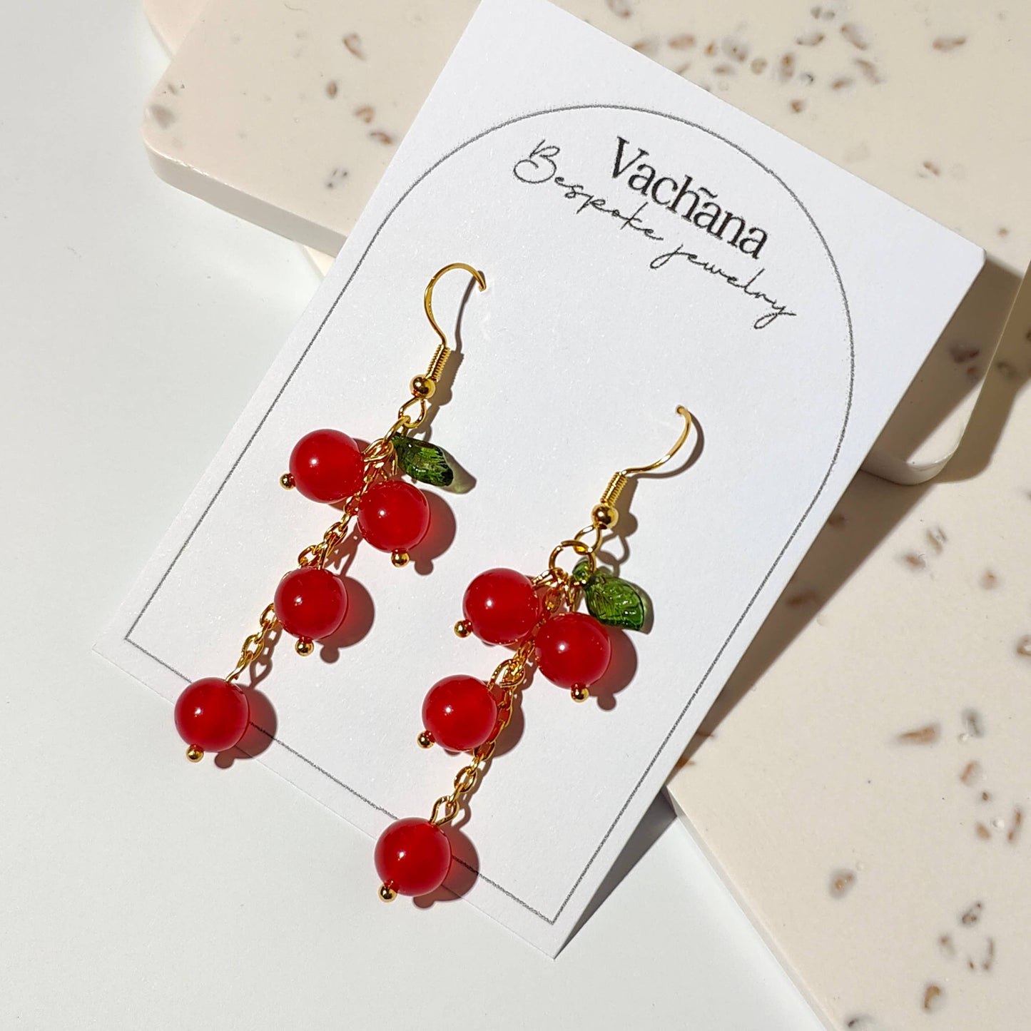 Cascade of red cherry gem stones with acrylic leaf on gold plated hooks