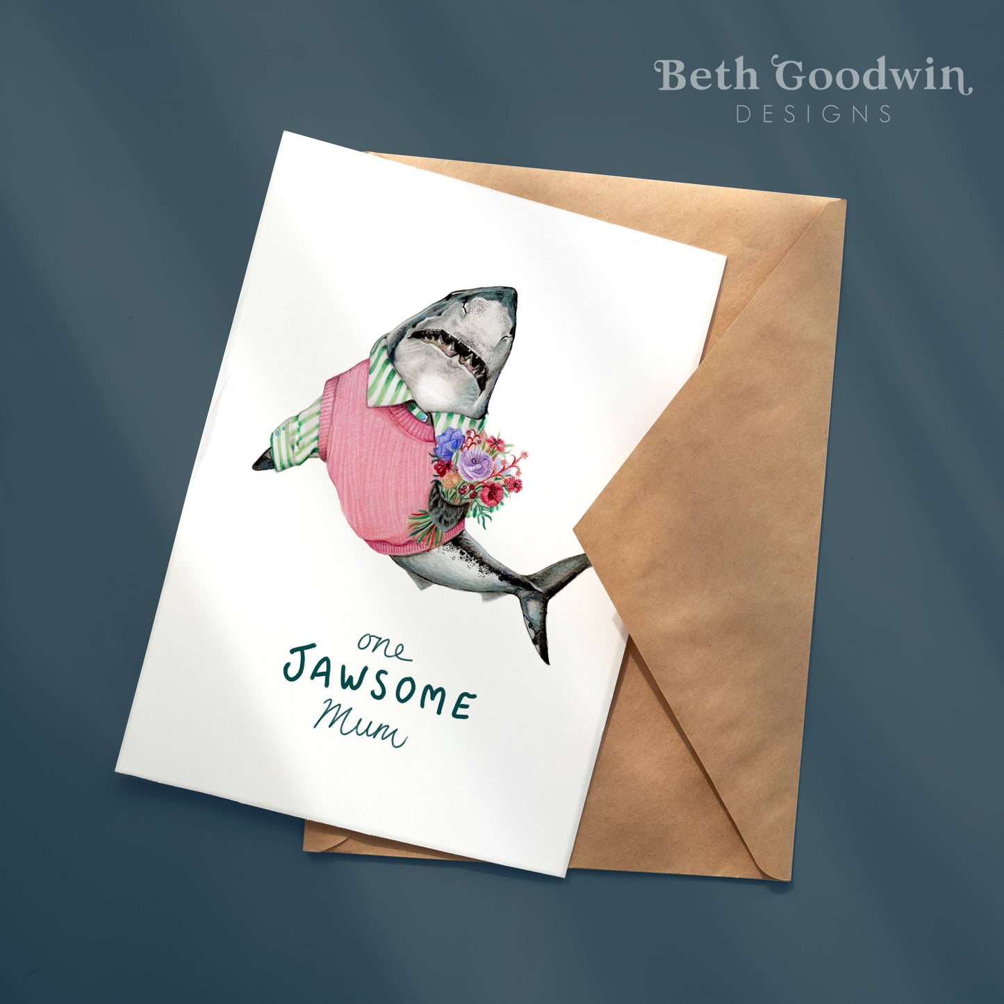 Greeting card with shark illustration and 'one Jawsome Mum' text, featuring a brown envelope on a dark blue background.