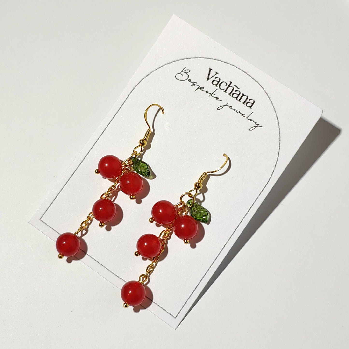 Cascade of red cherry gem stones with acrylic leaf on gold plated hooks