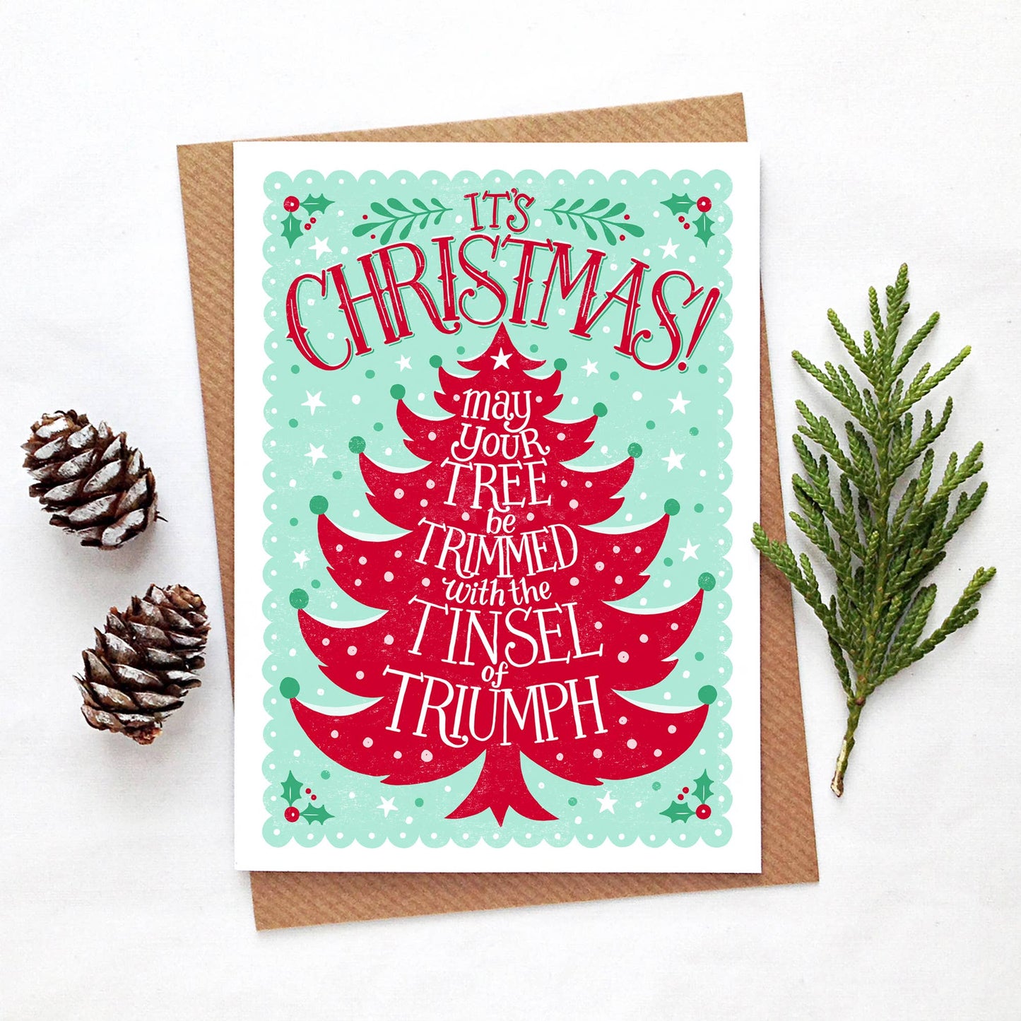 Christmas Card. Blank inside. Its Christmas may your tree be trimmed with the tinsel of triumph. A festive red Christmas tree with green background.