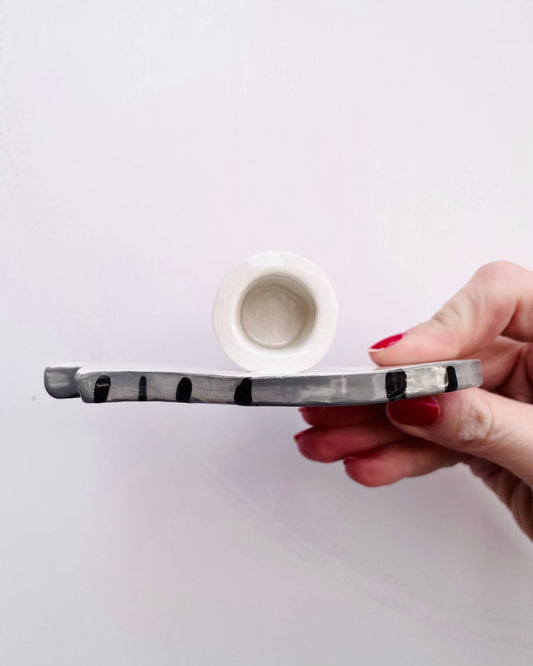 Hand holding a ceramic pipe with a white background