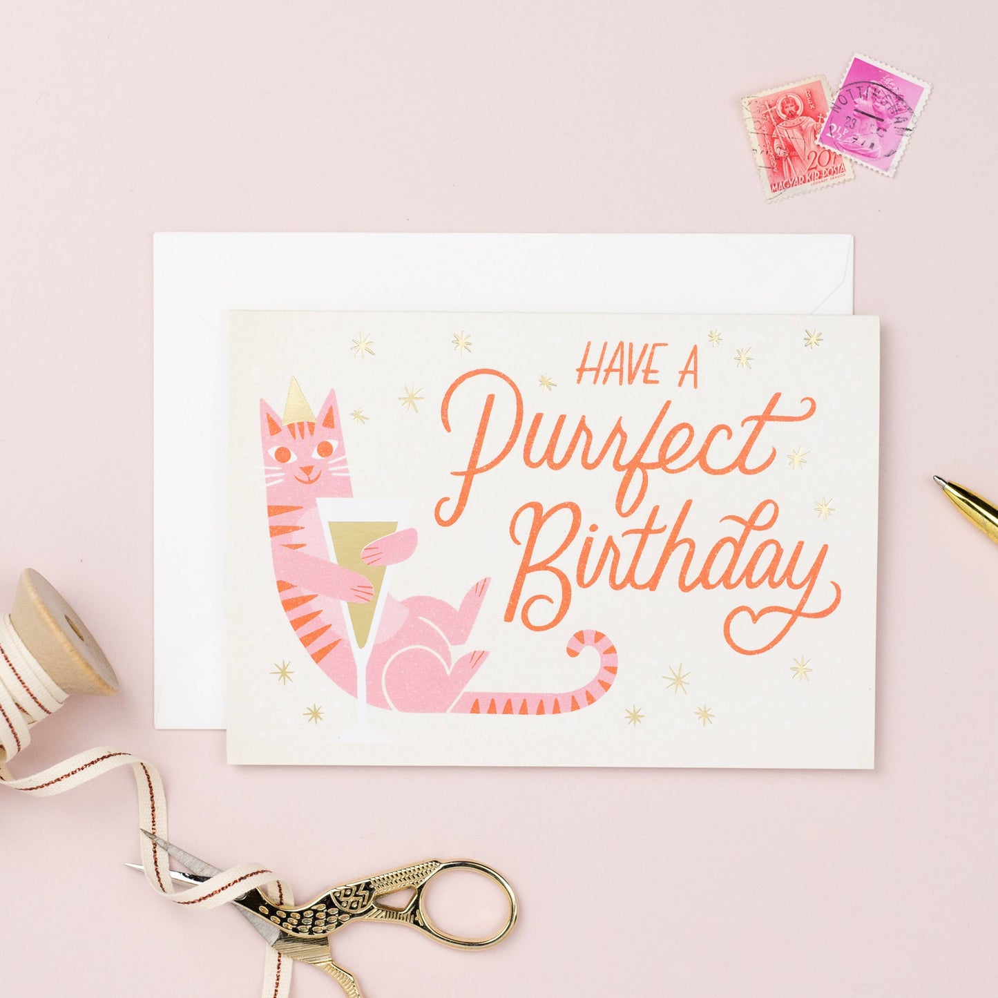 Birthday Card. Have a Perfect Birthday. A pink Stripy cat with a party hat and cuddling a glass of champagne.