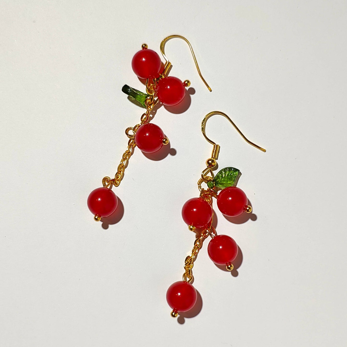 Cascade of red cherry gem stones with acrylic leaf on gold plated hooks