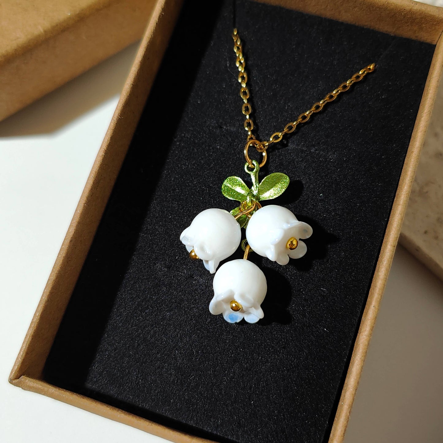 Glass lily of the valley charm hanging on gold plated chain.
