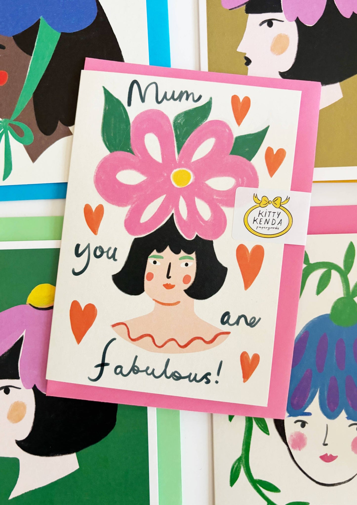 Card with illustration of a woman and a large pink flower, surrounded by colorful illustrations of women's faces.