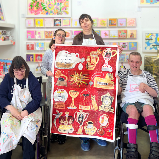 People holding a colorful tapestry in a room with art on the walls