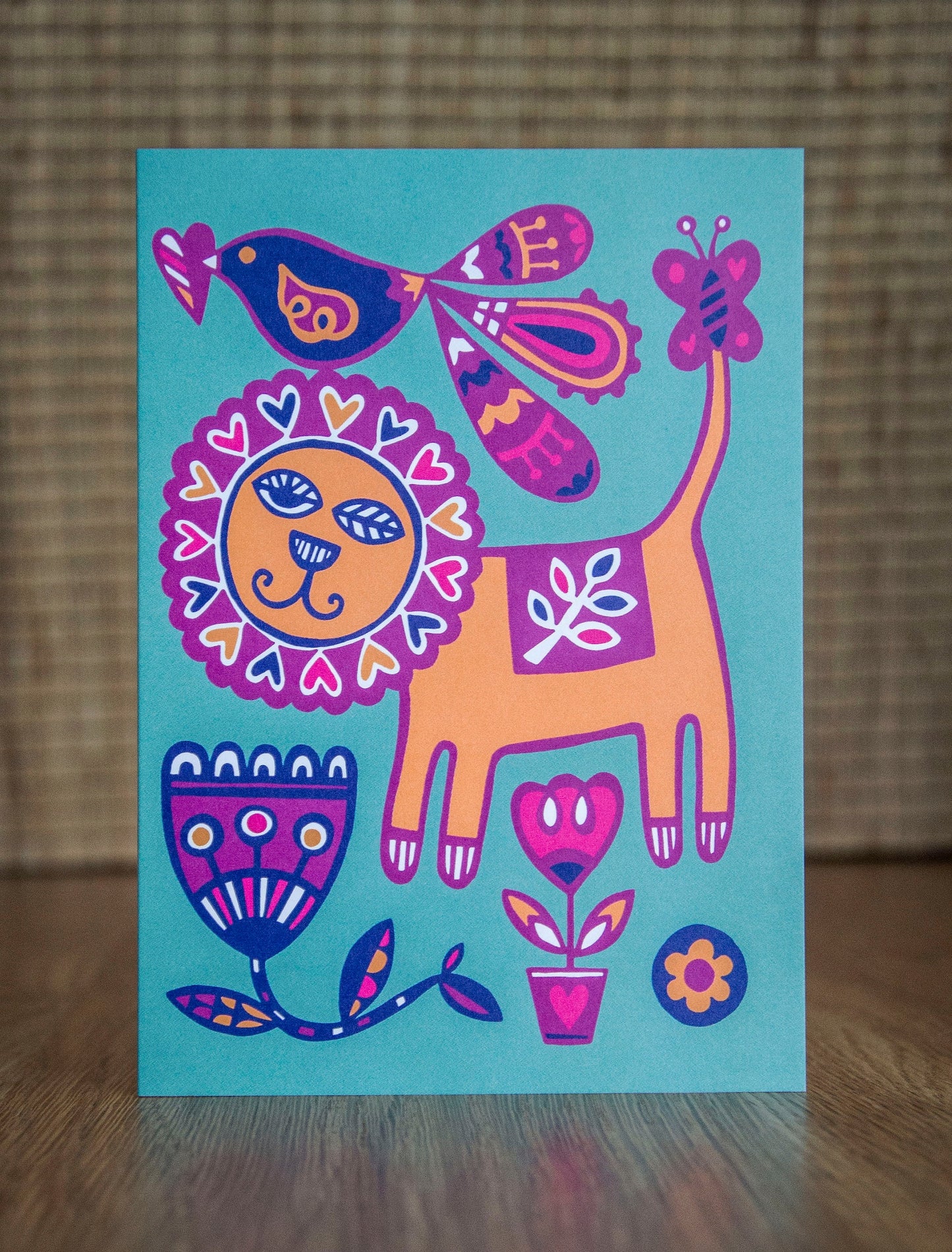 A bright and colourful image of a stylised art deco lion, bird and flowers.