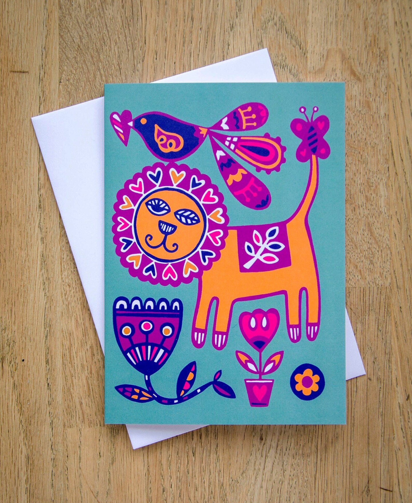 A bright and colourful image of a stylised art deco lion, bird and flowers.
