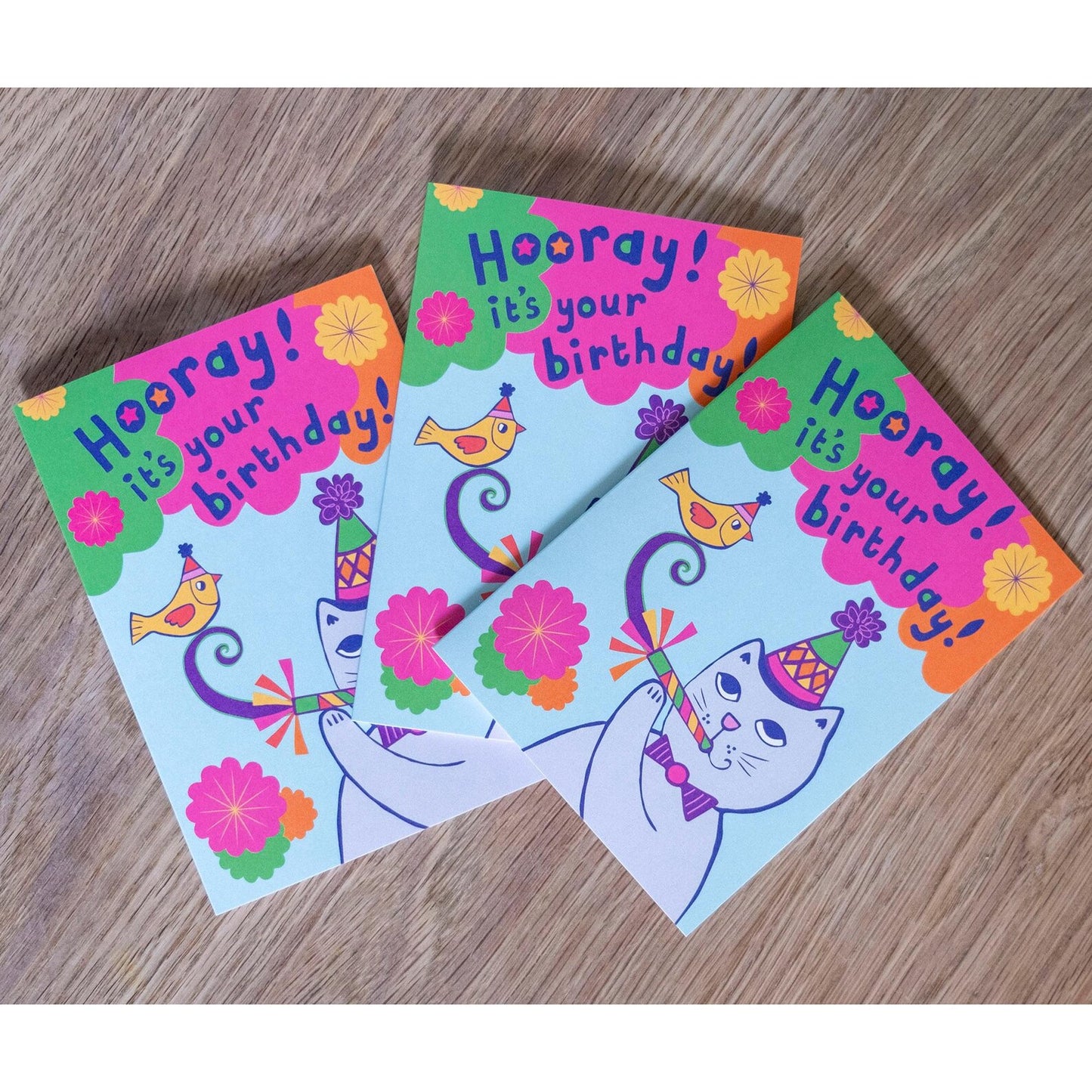 A card depicting a grey cat and yellow bird with party accessories, with the text "Hooray! It's your birthday!" above.